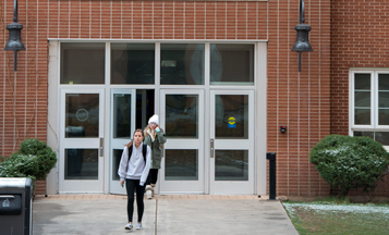 students walking out of a campus building